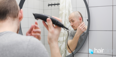 uomo che si rasa i capelli davanti lo specchio perché affetto da alopecia
