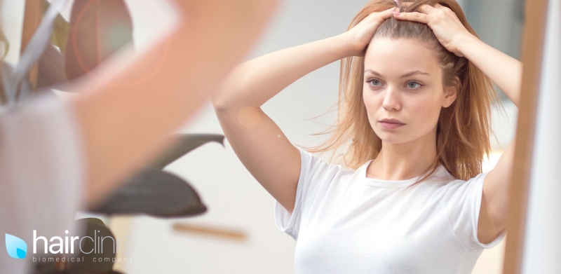 woman checking her hairline for hair loss